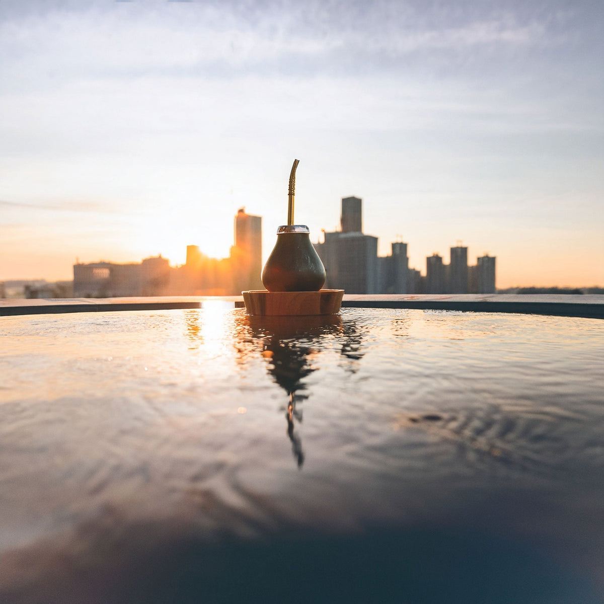 Yerba mate gourd floating in water with city skyscrapers and sunrise in the background — symbolizing the rise of the global mate movement.