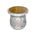 Premium handmade yerba mate cup displaying its natural wood core and an beautifully ornate metal repoussé exterior with traditional floral designs and warm brass details, shown against a minimalist white background.