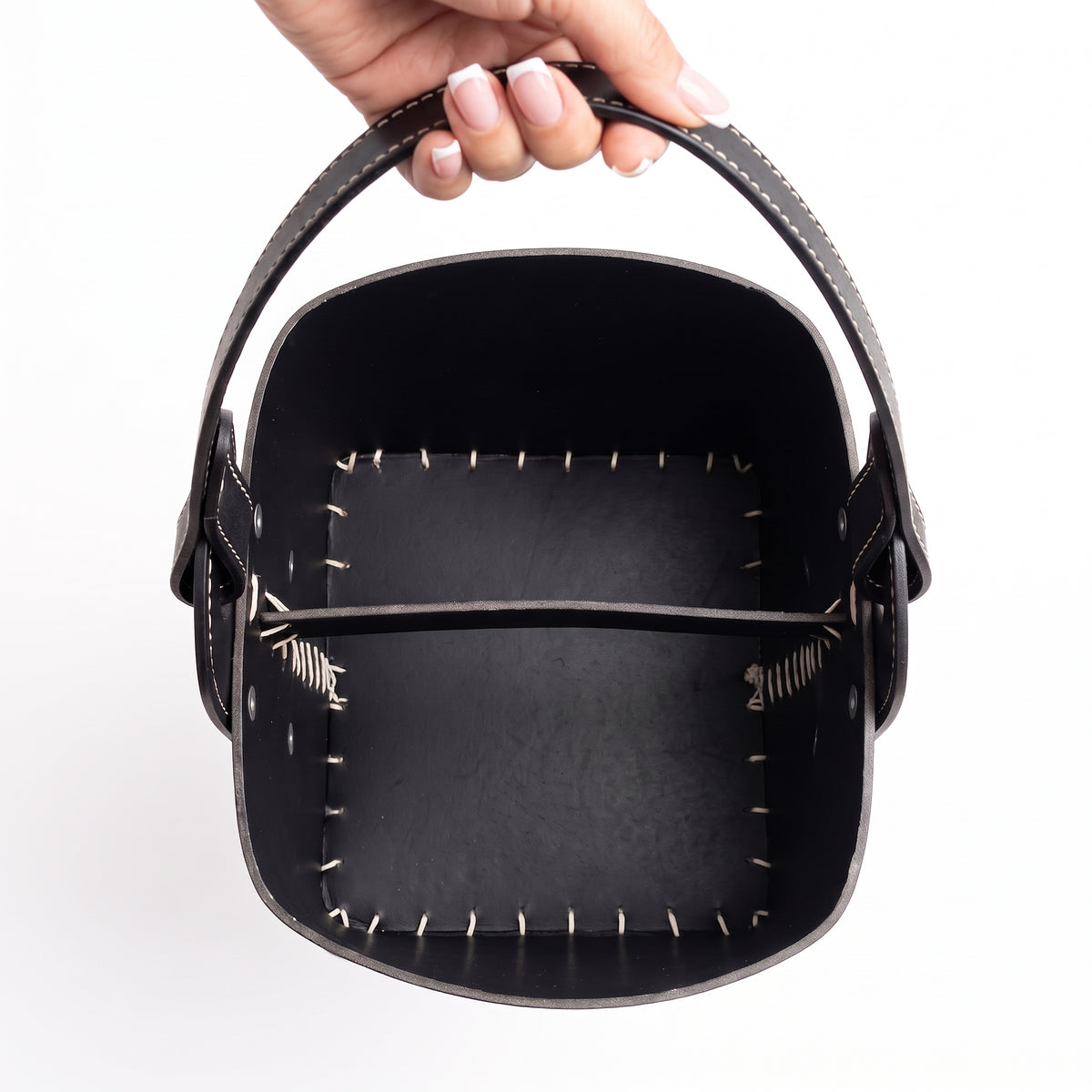 Top-down view of the interior of a black leather Patria Matera held by a hand. It features a robust internal leather divider and traditional white contrast hand-stitching along the base, set against a white background.