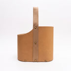 Side profile view of a light tan leather Uruguaya Matera featuring a vertical beige woven strap secured with brass-tone rivets, set against a plain white background.