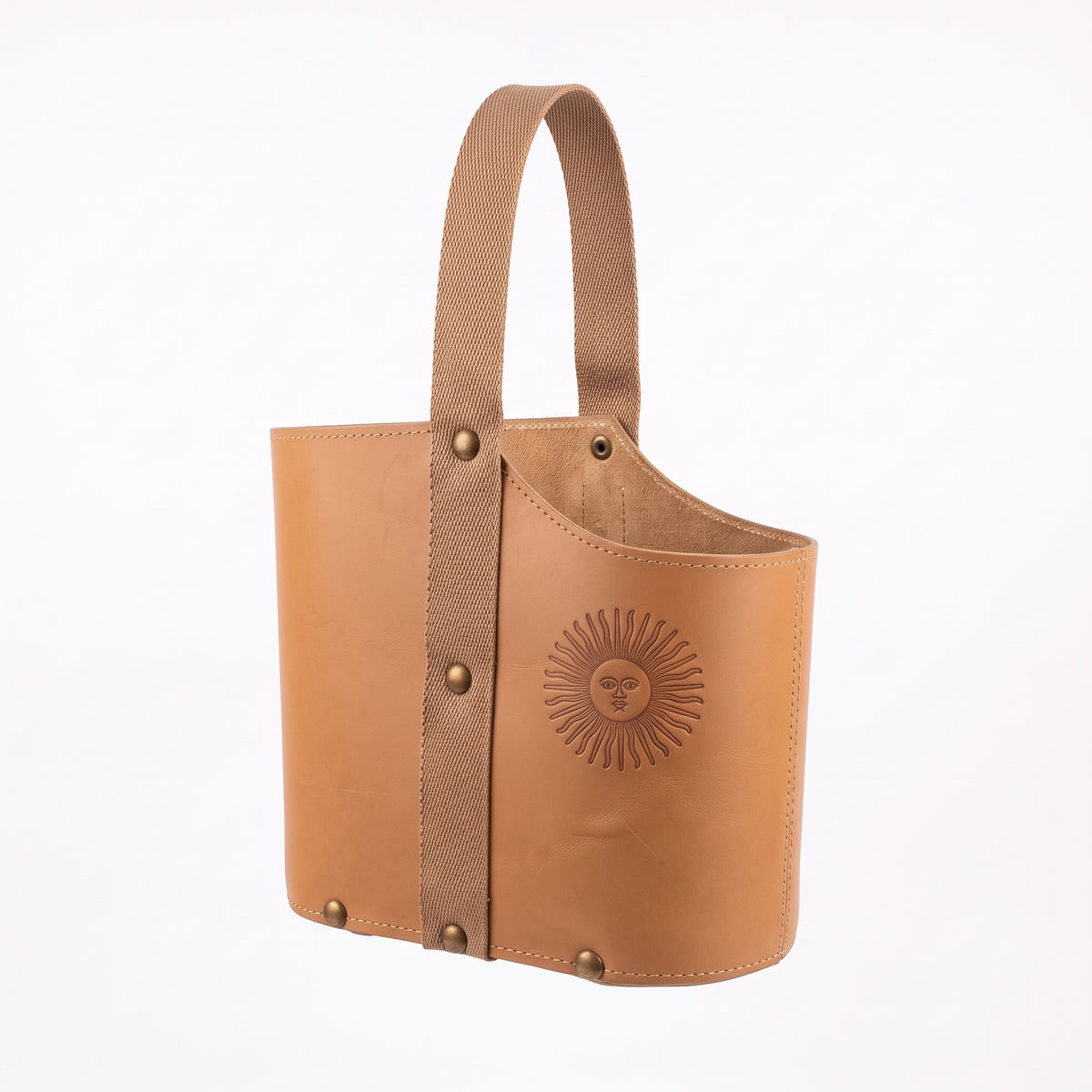 A light tan leather Uruguaya Matera featuring a matching beige woven strap, brass-tone rivets along the side and base, and an embossed Sun of May detail on the front, set against a plain white background.
