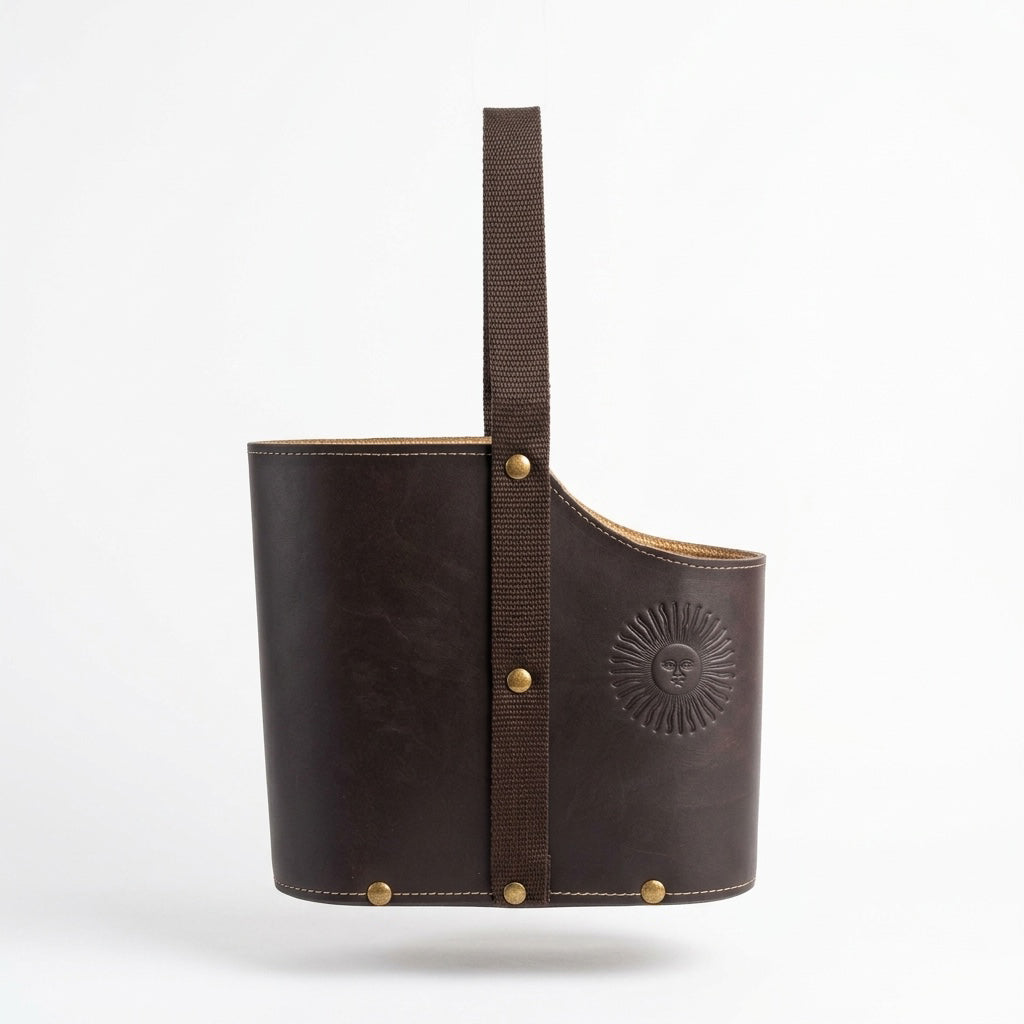 dark brown leather Uruguaya Matera featuring a matching brown woven nylon strap, brass-tone metal rivets along the base, and an embossed Sun of May design on the front, set against a plain white background.