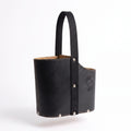 A black leather Uruguaya Matera with an ergonomic oval silhouette, a heavy-duty black woven nylon strap, silver-tone bottom rivets, and an embossed Sun of May design, set against a plain white background.