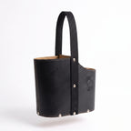 A black leather Uruguaya Matera with an ergonomic oval silhouette, a heavy-duty black woven nylon strap, silver-tone bottom rivets, and an embossed Sun of May design, set against a plain white background.