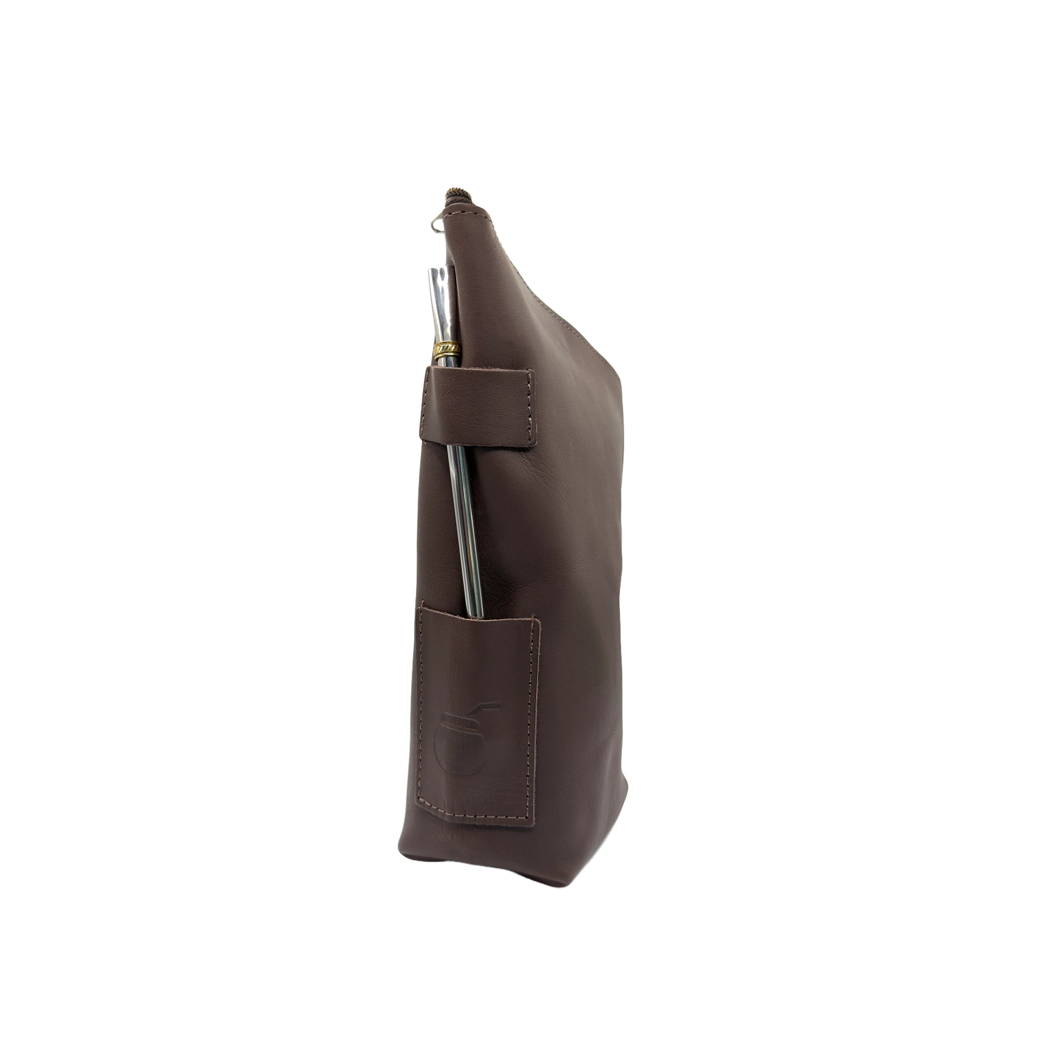 Side profile view of the handcrafted leather yerbera. This angle highlights the sturdy side pocket featuring an embossed mate gourd design, and the top zipper closure. A metal bombilla is inserted in the holder for display purposes only (bombilla sold separately).