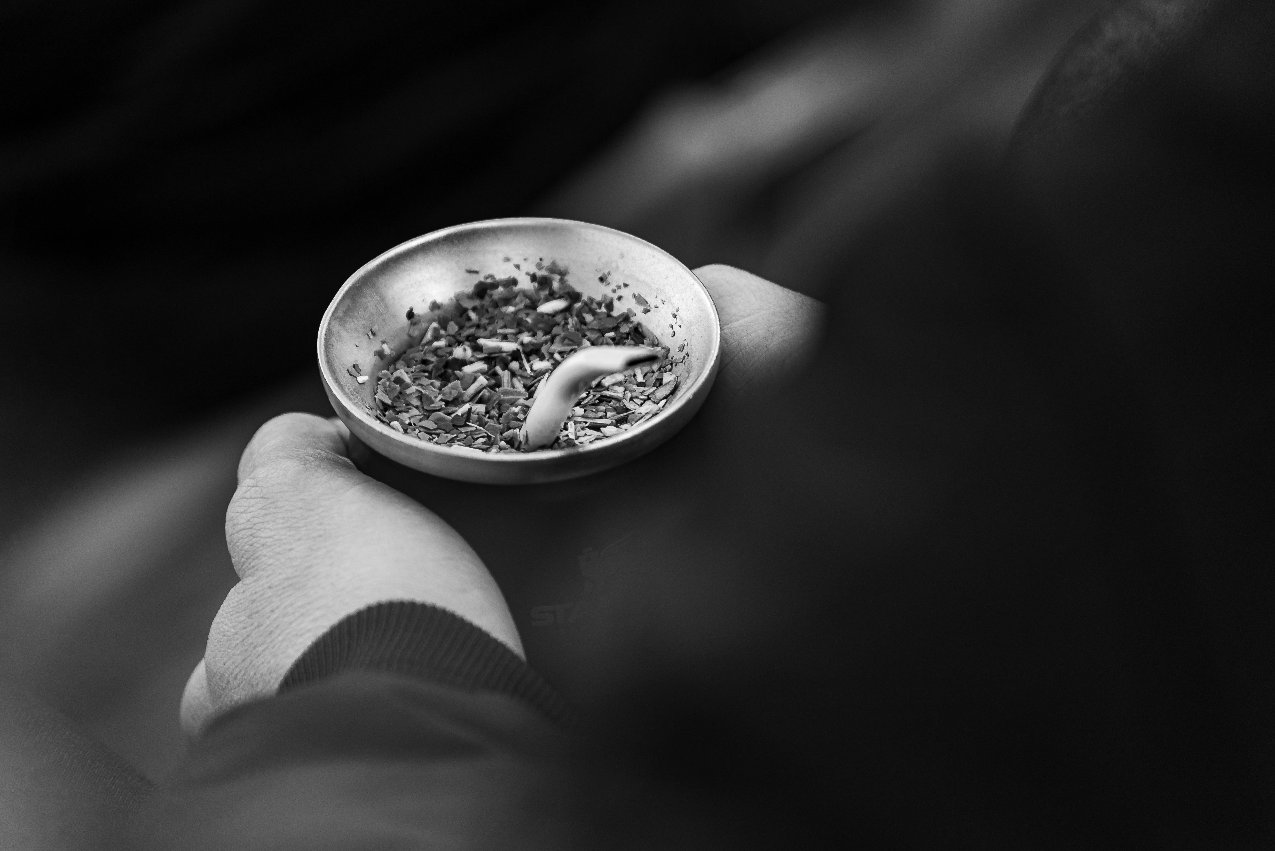 Hand holding a mate gourd against a dark background