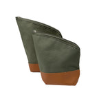 Two sage green Puelche yerba mate travel pouches standing upright. Made from flexible canvas with a protective brown eco-leather base and spill-proof diagonal zippers for easy pouring.