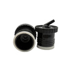 A close-up photograph displaying the two-pack of black Sur 360° stoppers on a white background. One stopper is positioned to show its internal screw-on thread and central red valve, while the other stands upright, revealing its distinctive precision pouring spout