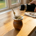 Serving yerba mate: steaming water pours from a black thermos into the handcrafted Tonada wooden gourd, which has the special silver sun bombilla shown in use.