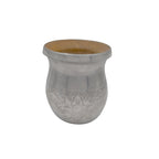 A clear front-angled view of the Vidala artisan mate gourd on a white background, showcasing the rich Algarrobo wood interior, the diagonally textured metal rim, and the hand-chiseled aluminum armour with rustic floral motifs.
