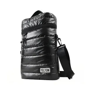 An angled, three-quarter view of the YELTON black puffer mate bag on a pure white background. This angle emphasizes the bag's rectangular structure, the depth of the quilted padding, the attached crossbody strap, and the top carrying handle.